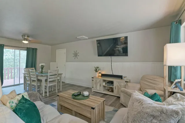 a living room with furniture a flat screen tv and kitchen view