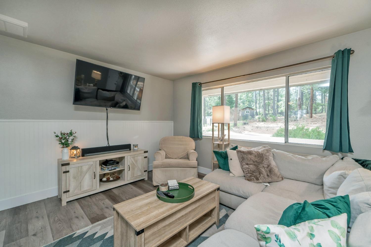 5781 Sly Park Road Pollock Pines, CA 95726 - Photo 20 of 40 a living room with furniture a flat screen tv and a large window