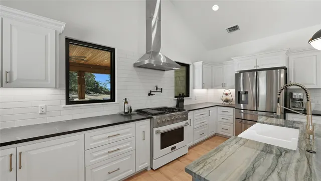 a kitchen with stainless steel appliances granite countertop a sink a stove and a wooden floors