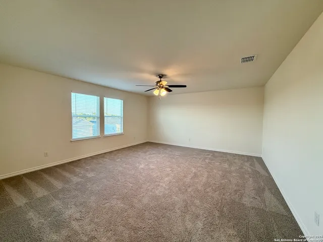 an empty room with windows and ceiling fan view