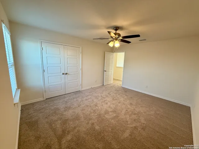 an empty room with windows and fan
