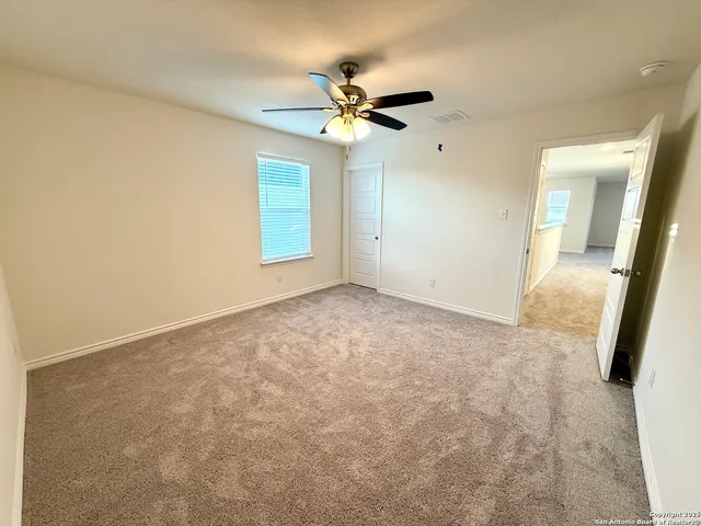 an empty room with windows and fan
