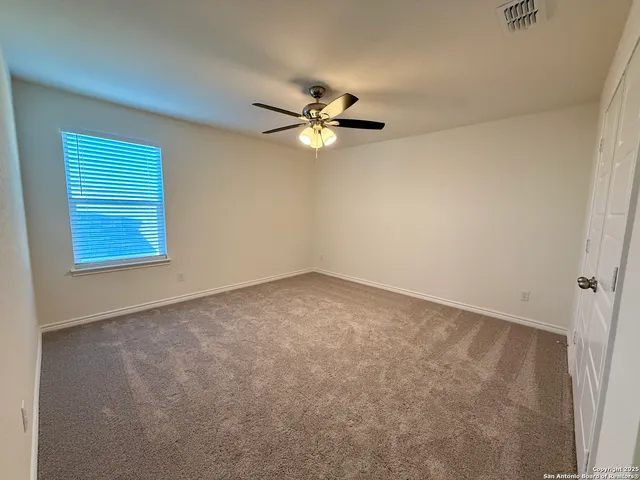 an empty room with a window and a ceiling fan