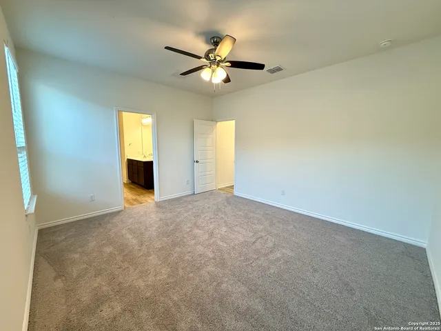 an empty room with windows and fan