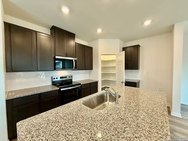 a kitchen with stainless steel appliances kitchen island granite countertop a sink dishwasher stove and refrigerator with wooden floor