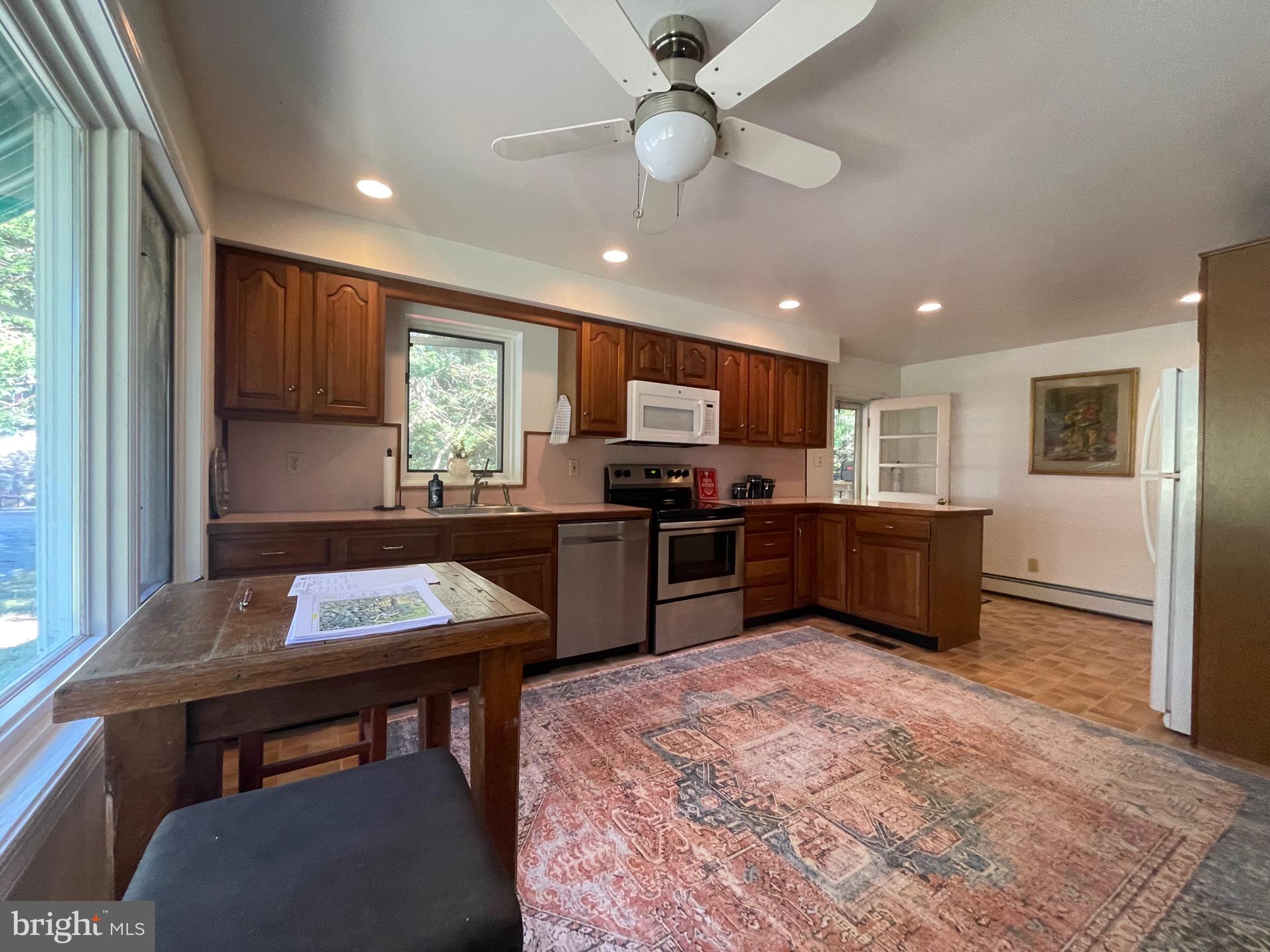 120 Diamond Rock Road Phoenixville, PA 19460 - Photo 25 of 86 a kitchen with a refrigerator a microwave oven a sink a dining table and chairs with wooden floor