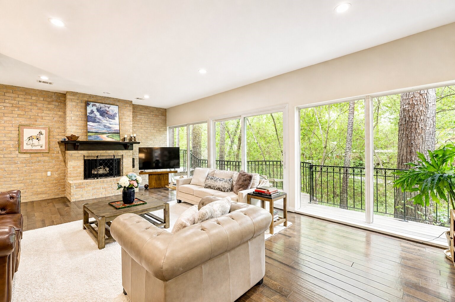 201 Vanderpool Lane, Unit 130 Houston, TX 77024 - Photo 3 of 41 Another view of the sunken living room. The space is grounded by an exposed brick wall and fireplace and raised hearth. The dark, rich hardwood flooring complements the wooden views beyond.