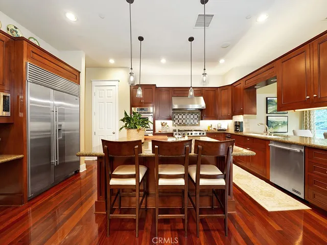 a kitchen with stainless steel appliances granite countertop wooden floors stove and white cabinets