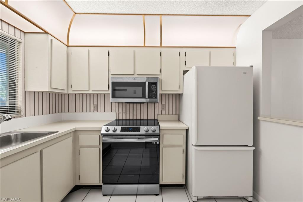 4251 27th Court Southwest, Unit 104 Naples, FL 34116 - Photo 10 of 22 a kitchen with white cabinets and white appliances