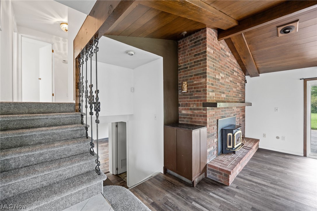 27299 Belgrave Road Cleveland, OH 44124 - Photo 4 of 11 Stairway featuring brick wall, wooden ceiling, a fireplace, light hardwood flooring, and vaulted ceiling with beams