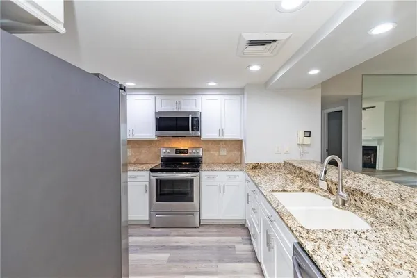 a kitchen with stainless steel appliances granite countertop a refrigerator stove and sink