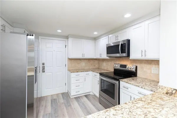a kitchen with granite countertop a sink a stove and microwave
