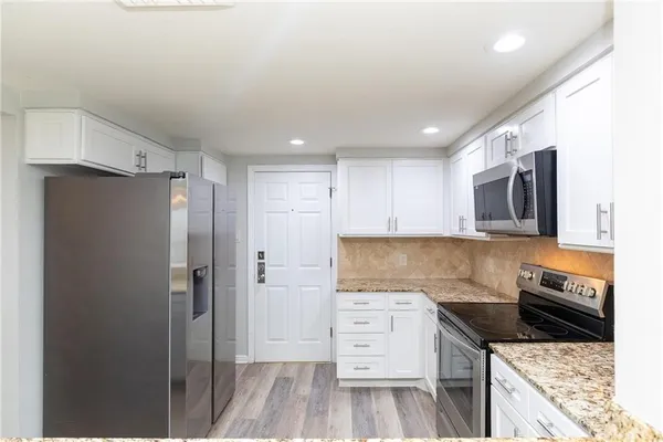 a kitchen with granite countertop a stove top oven microwave and cabinets