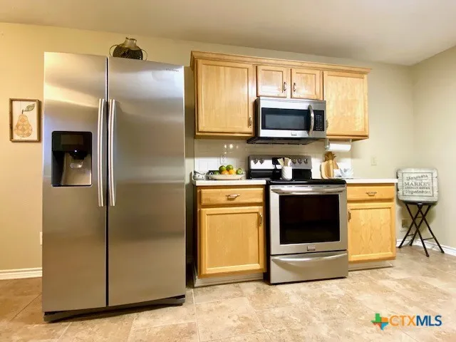 a kitchen with stainless steel appliances granite countertop a refrigerator a stove and a sink with granite countertops