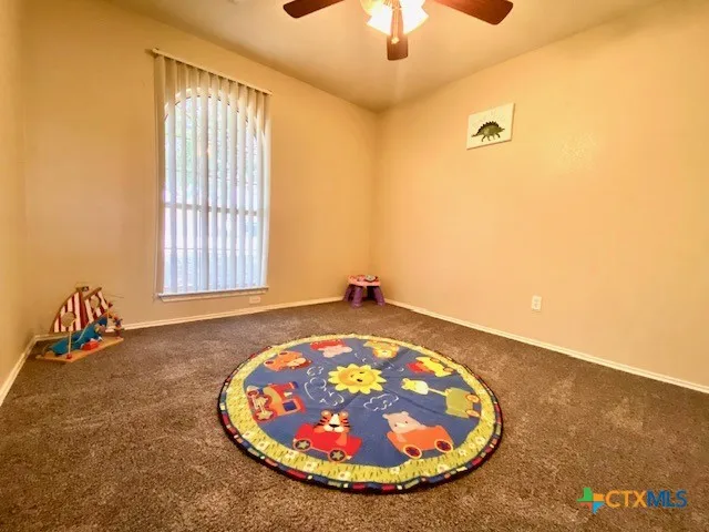 a view of an empty room with window and chandelier fan