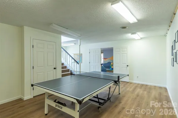 a room with pool table wooden floor and windows