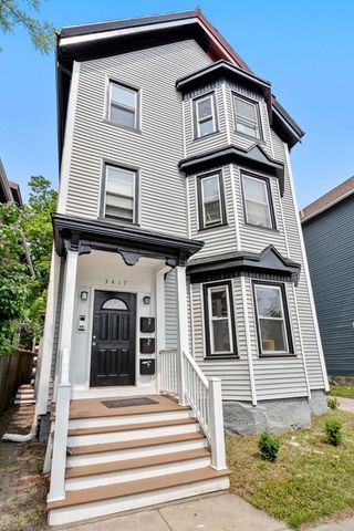 a view of a white house with large windows and a small yard