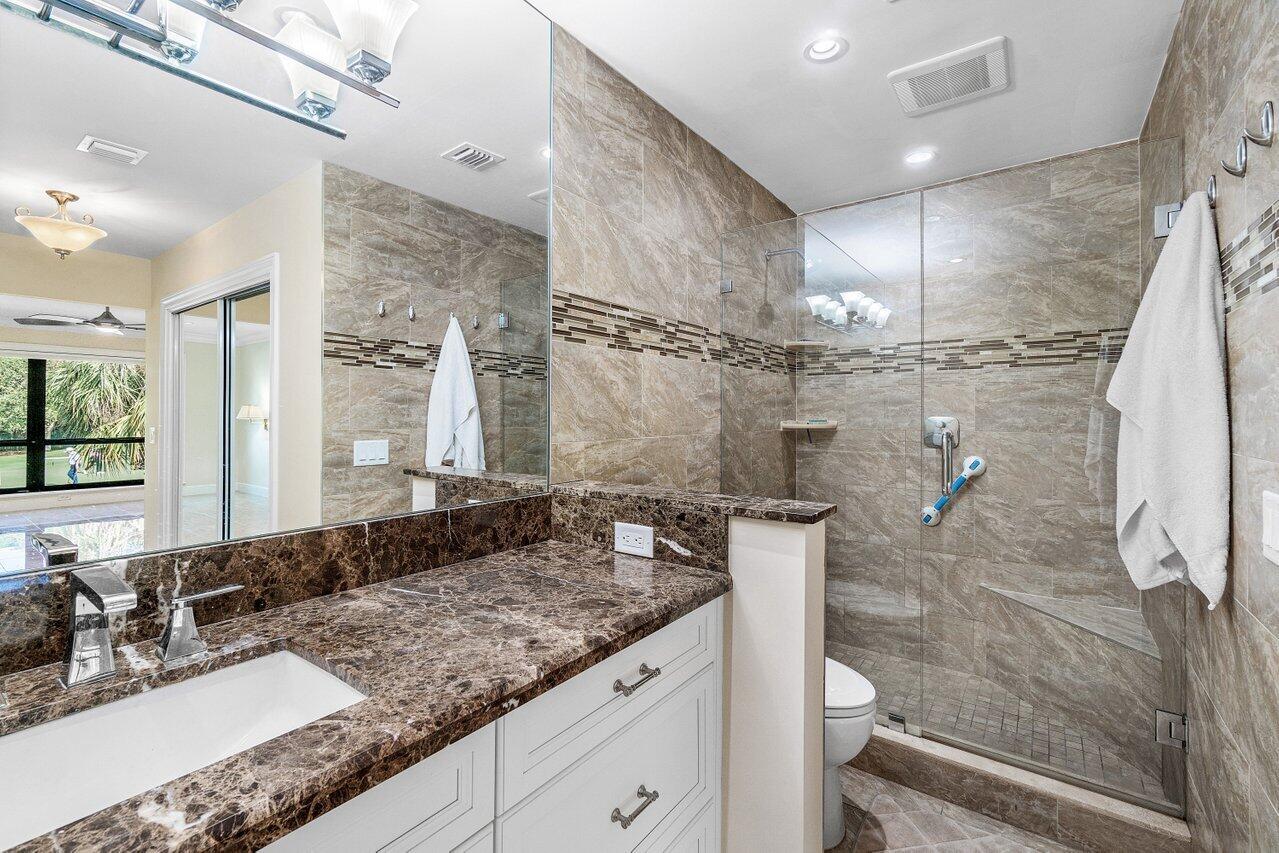 11110 Quail Covey Road, Unit MOCKINGBIRD Boynton Beach, FL 33436 - Photo 25 of 45 a bathroom with a granite countertop sink a toilet and shower