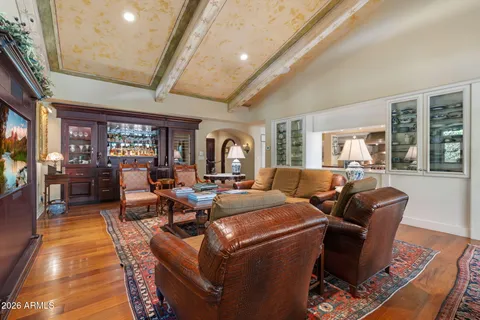 a living room with furniture large windows and wooden floor