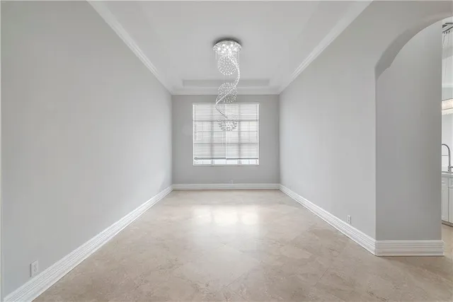 an empty room with windows and chandelier fan