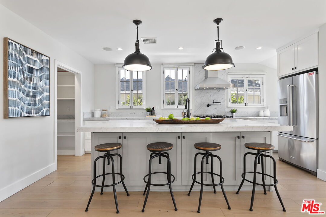 6507 West Olympic Boulevard Los Angeles, CA 90048 - Photo 16 of 50 a kitchen with stainless steel appliances a dining table chairs and white cabinets