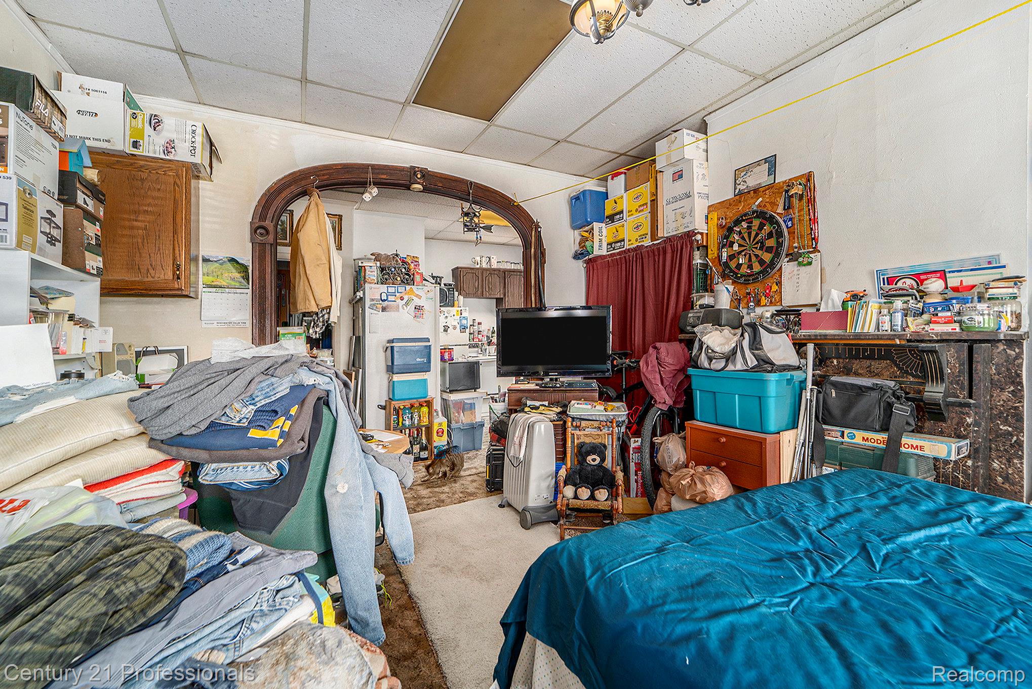 Bedroom with a drop ceiling, carpet floors, and freestanding refrigerator