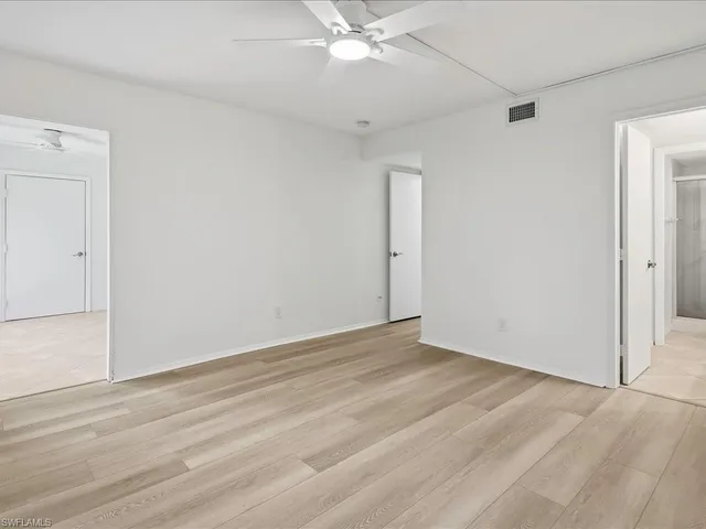an empty room with a ceiling fan and wooden floor