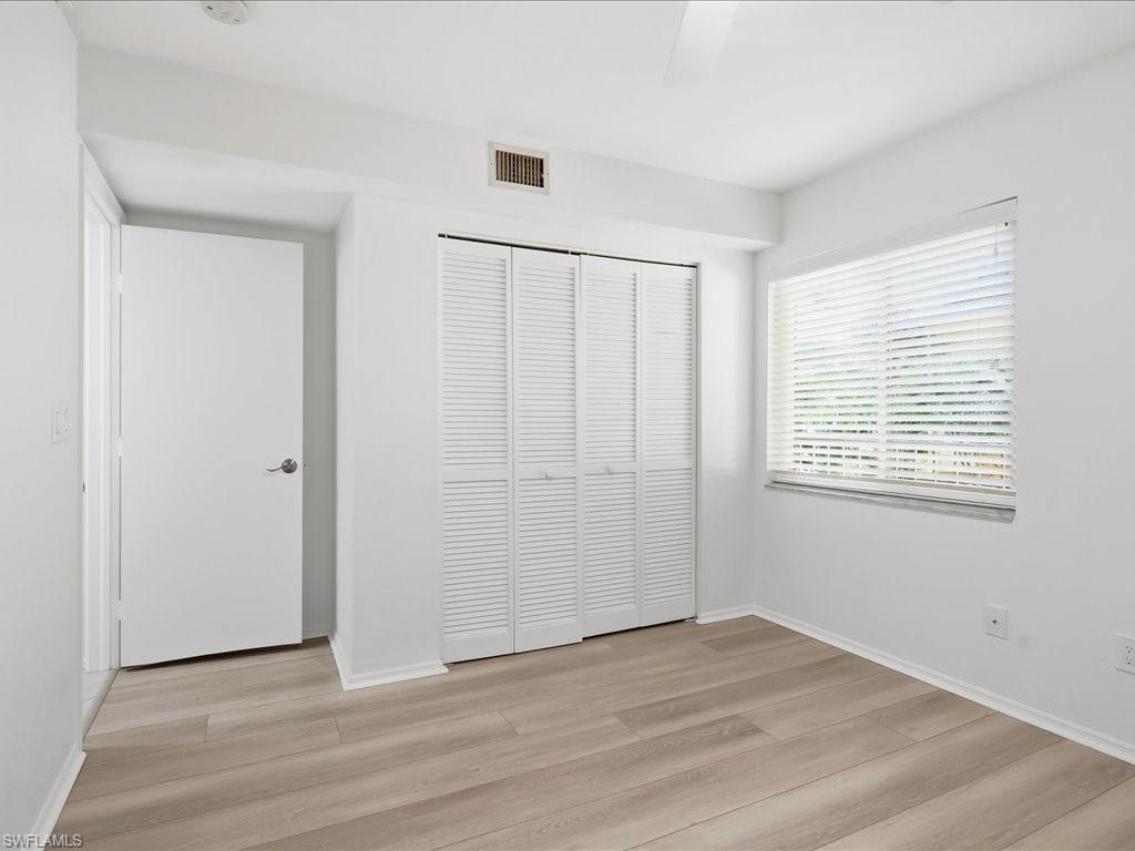 1001 Foxfire Lane, Unit 204 Naples, FL 34104 - Photo 19 of 35 a view of an empty room with wooden floor and a window