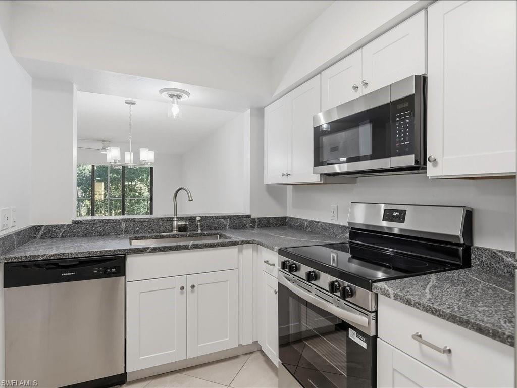1001 Foxfire Lane, Unit 204 Naples, FL 34104 - Photo 2 of 35 a kitchen with granite countertop a sink stove and microwave
