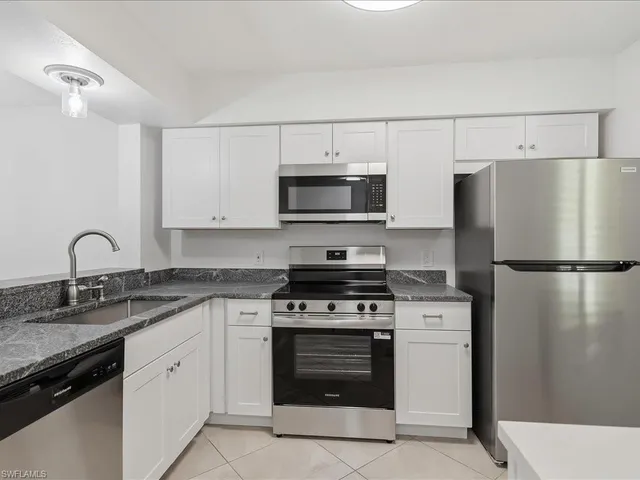 a kitchen with white cabinets and stainless steel appliances