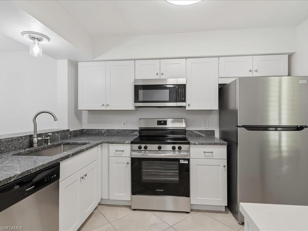 1001 Foxfire Lane, Unit 204 Naples, FL 34104 - Photo 4 of 35 a kitchen with white cabinets and stainless steel appliances