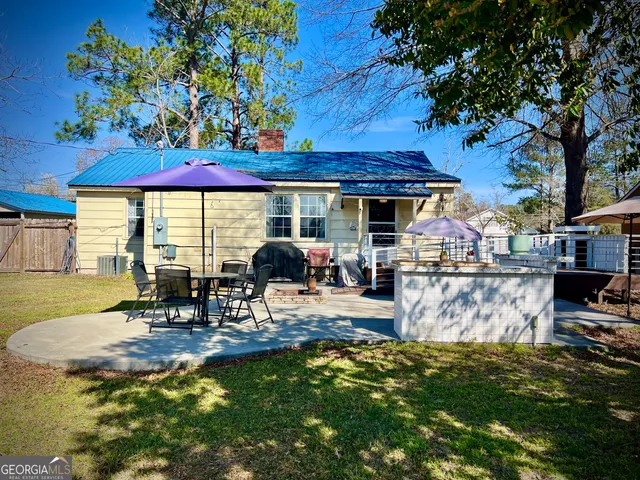 a view of a patio with table and chairs potted plants and large tree