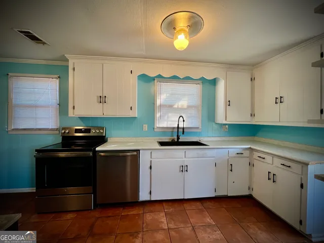 a kitchen with stainless steel appliances granite countertop a stove a sink and a microwave