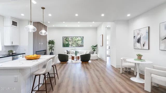 a kitchen with stainless steel appliances a dining table chairs stove refrigerator and cabinets