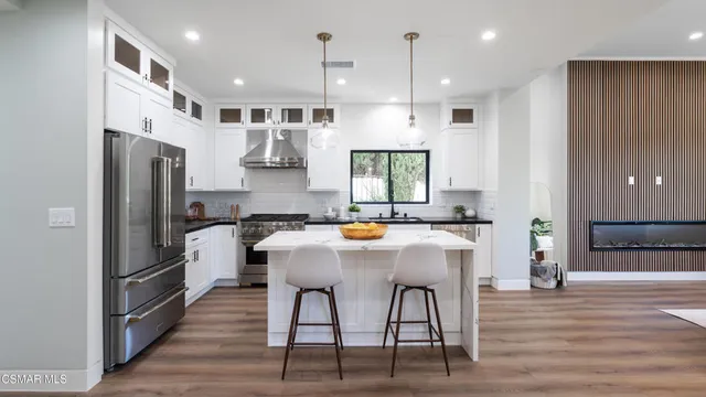 a kitchen with stainless steel appliances granite countertop a stove refrigerator and a wooden floor