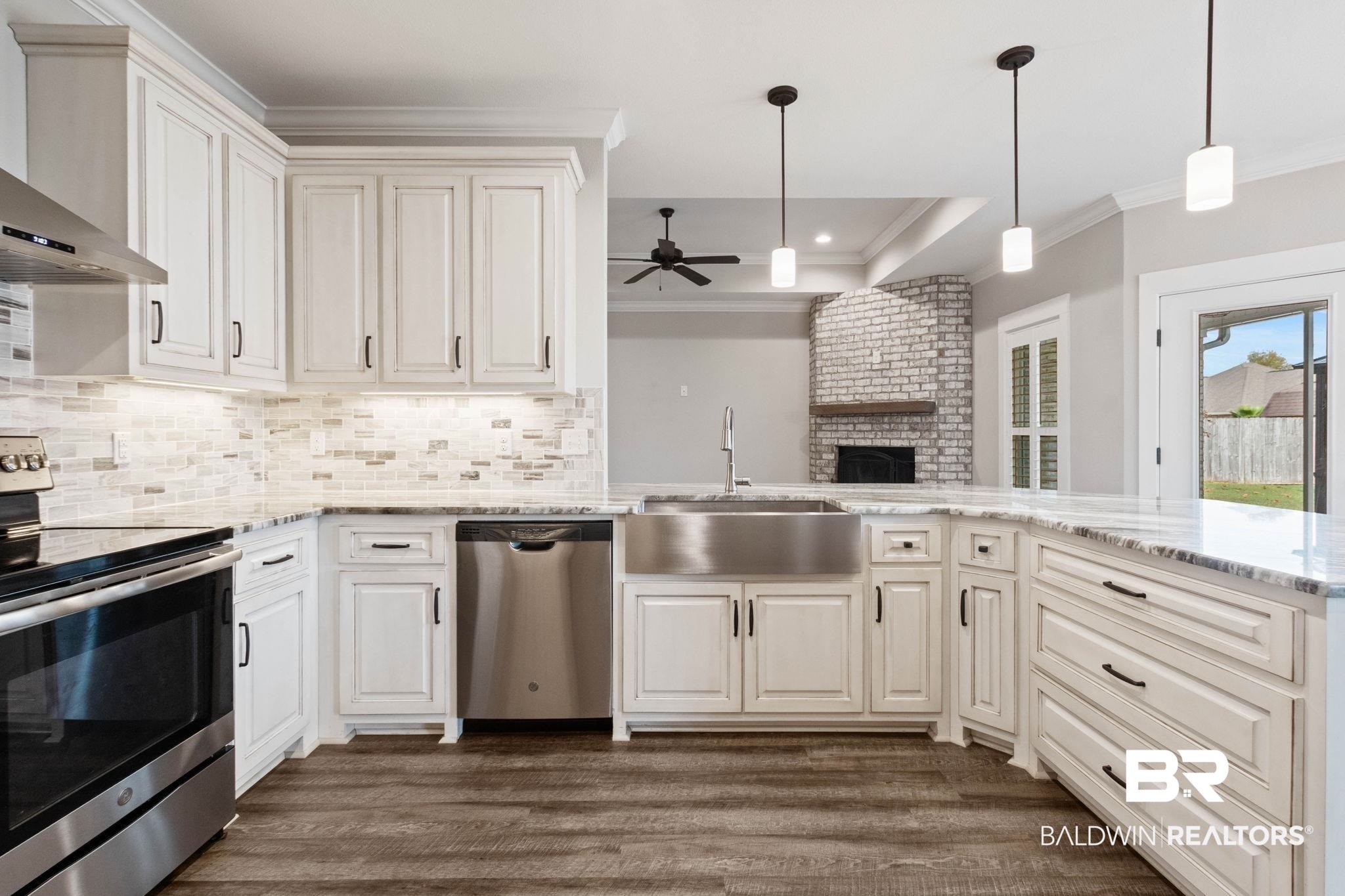 17376 Bankhead Boulevard Fairhope, AL 36532 - Photo 22 of 73 Kitchen with stainless steel appliances, light stone counters, wall chimney range hood, ornamental molding, and decorative light fixtures