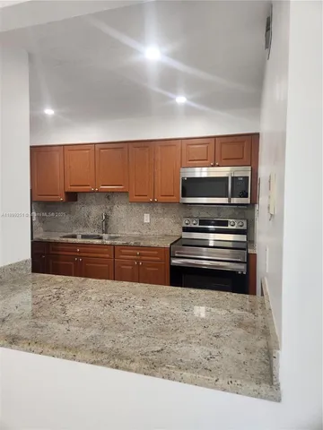 a kitchen with stainless steel appliances granite countertop a stove a sink and a microwave