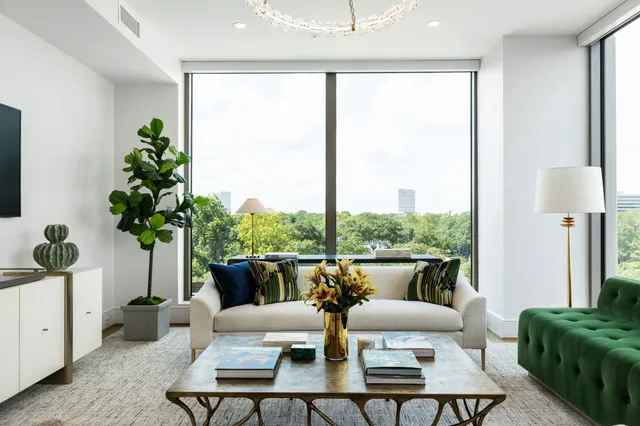 a living room with stainless steel appliances furniture a rug and a kitchen view