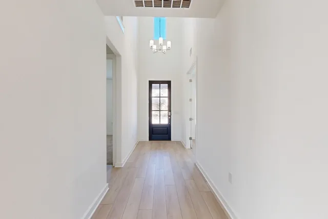 a view of a hallway with wooden floor and a chandelier