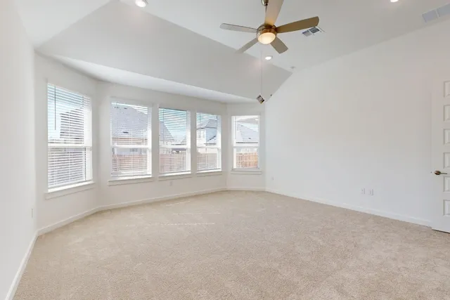 an empty room with chandelier fan and windows