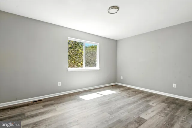 a view of an empty room with wooden floor and closet