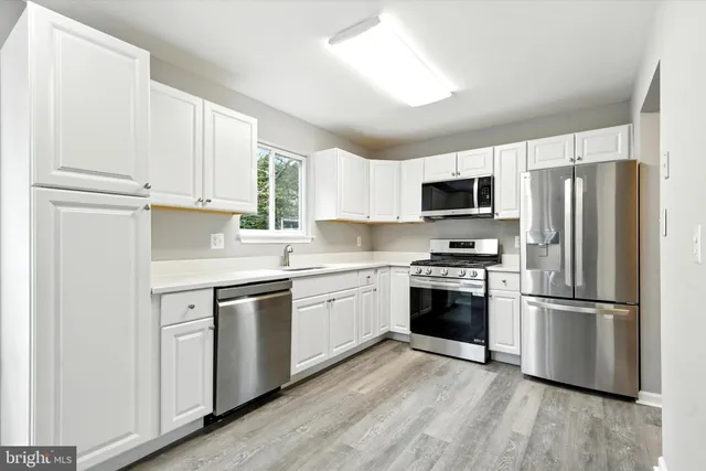 a kitchen with white cabinets and stainless steel appliances