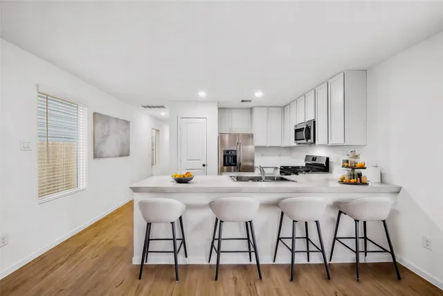 a kitchen with stainless steel appliances kitchen island granite countertop a dining table chairs and granite counter tops