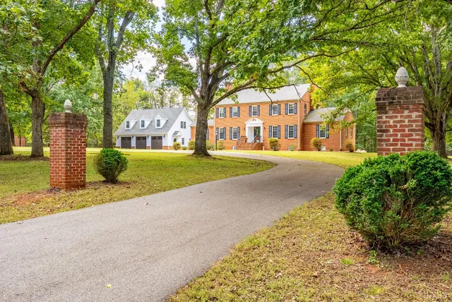 a front view of a house with a garden and trees