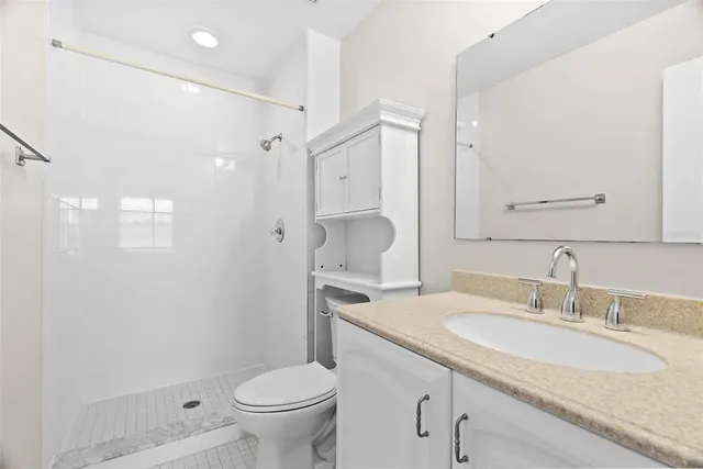 a bathroom with a granite countertop sink a toilet and a mirror