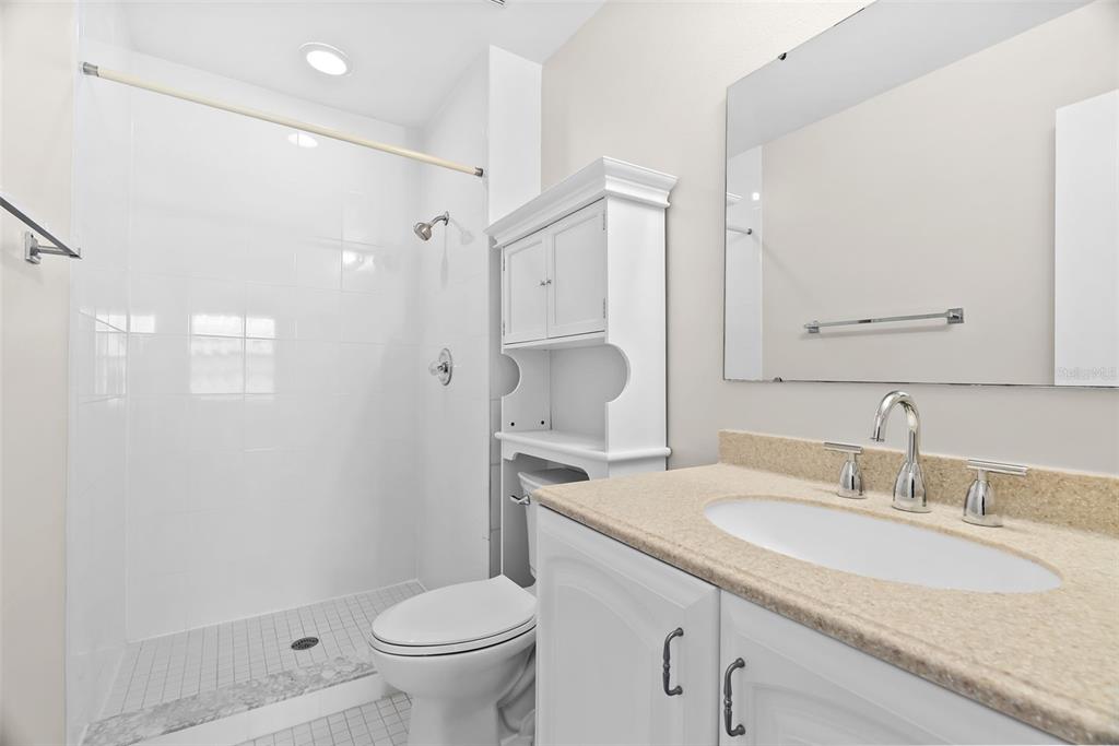 12668 Castle Hill Drive Tampa, FL 33624 - Photo 18 of 32 a bathroom with a granite countertop sink a toilet and a mirror