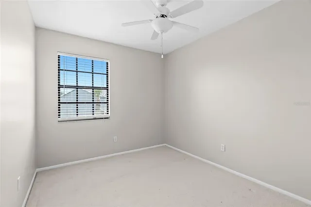 an empty room with a window and ceiling fan