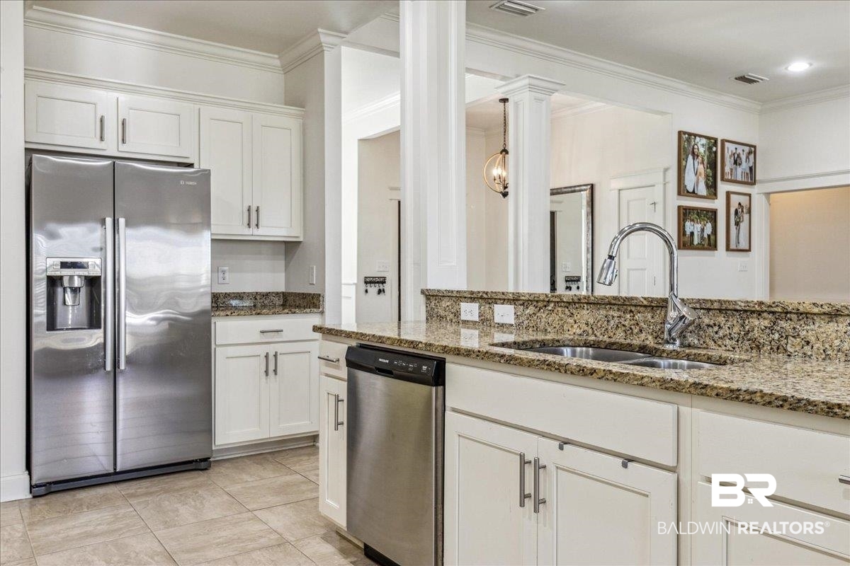 7088 Rocky Rd Loop Gulf Shores, AL 36542 - Photo 11 of 39 Kitchen with appliances with stainless steel finishes, ornamental molding, white cabinets, light stone countertops, and ornate columns
