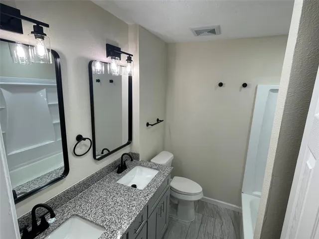 a bathroom with a granite countertop sink toilet and shower