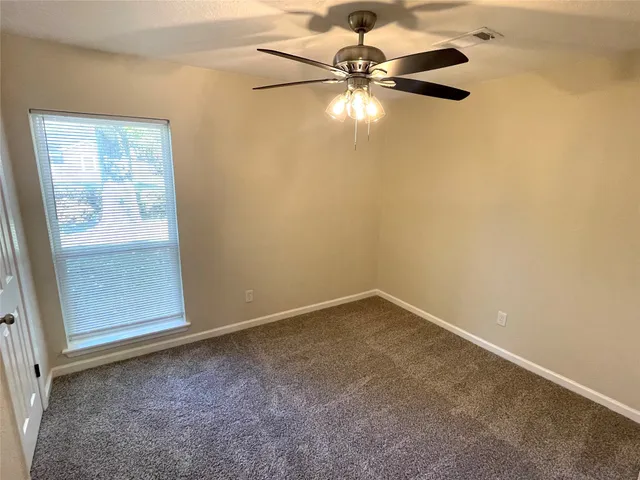 an empty room with a fan & a window